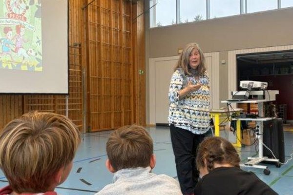 Die Autorin Bettina Obrecht liest den Dritt- und Viertklässlern aus ihrem Buch P.F.O.T.E. vor. Die Kinder hören interessiert zu.